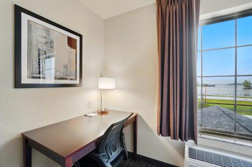 a hotel room with a desk and a window at Cobblestone Hotel & Suites - Russells Point at Indian Lake in Russells Point