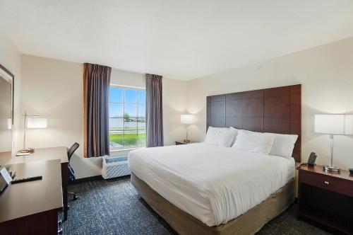 Russells PointCobblestone Hotel & Suites - Russells Point at Indian Lake的有一张大床和一扇窗户的酒店房间