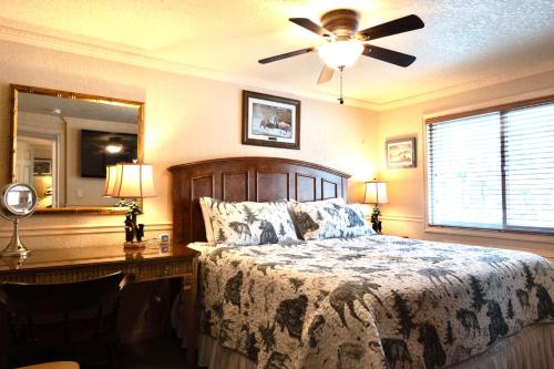 a bedroom with a bed and a desk and a ceiling fan at Yellowstone Gateway Inn in Gardiner