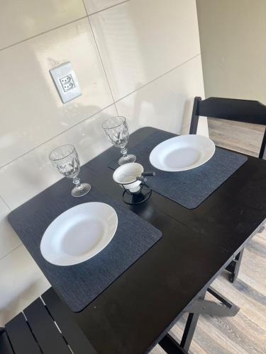 a black table with two plates and wine glasses on it at Chalés do vale Extrema verde in Extrema