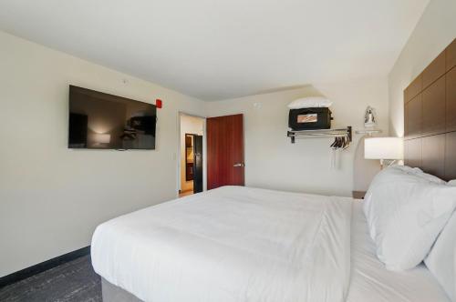 a bedroom with a large white bed and a tv at Cobblestone Hotel & Suites - Russells Point at Indian Lake in Russells Point