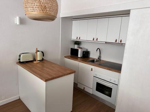 eine Küche mit weißen Schränken und einer Holzarbeitsplatte in der Unterkunft Vilamoura Living 106 in Quarteira