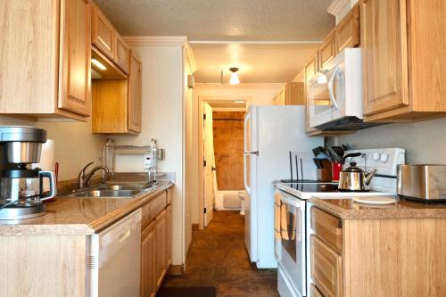a kitchen with wooden cabinets and a white refrigerator at Yellowstone Gateway Inn in Gardiner