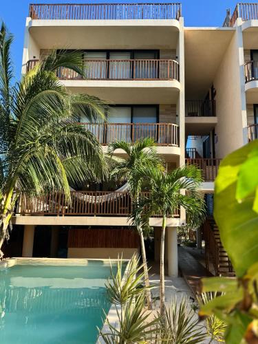 an apartment building with a swimming pool in front of it at Sunset 2BR Apartment Steps from the Beach with Ocean View in Holbox Island