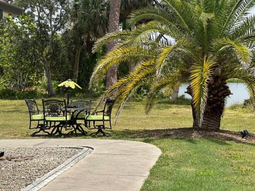 a table and chairs under a palm tree in a park at Magic Secluded Suite-Pool-Sauna plus Lake View Venice Florida in Venice