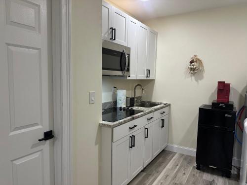 a kitchen with white cabinets and a sink and a microwave at Magic Secluded Suite-Pool-Sauna plus Lake View Venice Florida in Venice