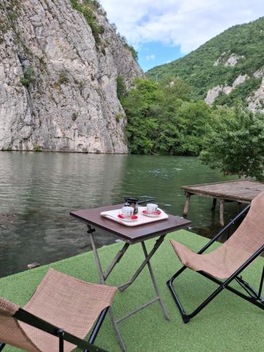 a picnic table and two chairs next to a river at Moravski konak- Moravian Inn in Ovčar Banja