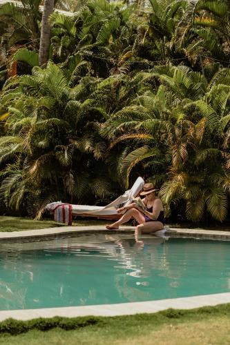 a woman sitting on the edge of a swimming pool at Solea Villa Tropical in Santa Marta
