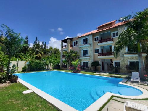 a villa with a swimming pool in front of a building at New! Chic Beach Condo at Punta Cana in Punta Cana