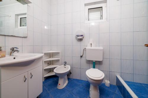 a white bathroom with a toilet and a sink at Apartments Mirela in Karlobag