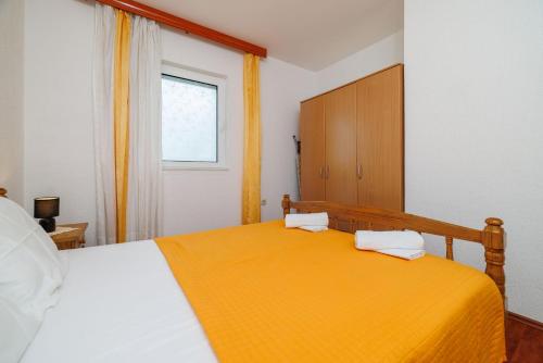 a bedroom with a large bed with an orange blanket at Apartments Mirela in Karlobag