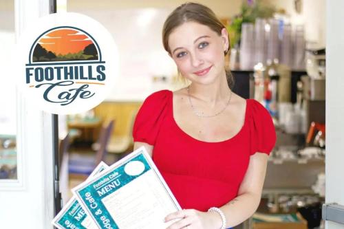 a woman in a red dress holding a clipboard at Foothills Lodge & Diner in Malone