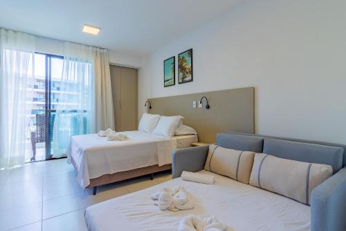 ein Hotelzimmer mit zwei Betten und einer Couch in der Unterkunft Malia Beach #D105 - Muro Alto por Carpediem in Ipojuca