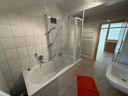 a bathroom with a tub and a shower and a sink at Lisa & Gretl's Alpen-Panorama Chalet Saalfelden - 10 Min nach Zell am See in Saalfelden am Steinernen Meer