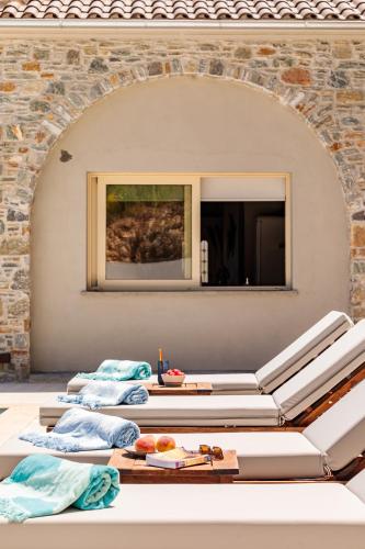 a room with three lounge chairs and a wall with a mirror at Villa Nanoula & Villa Stella Twin Villas Retreat in Skopelos Town