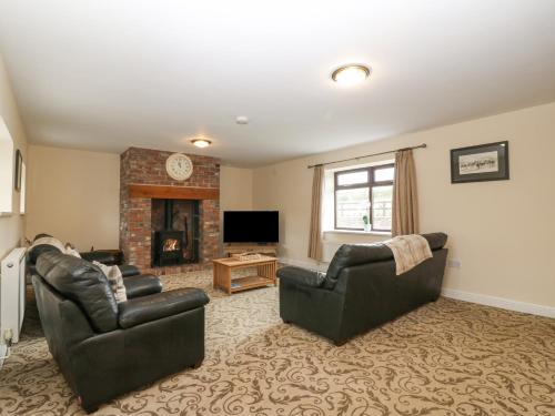 a living room with two chairs and a fireplace at Yr Hen Stabl in Caernarfon