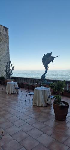 a patio with two tables and a statue of a dragon at Torre Perrotti - Le suite in Santa Maria di Castellabate