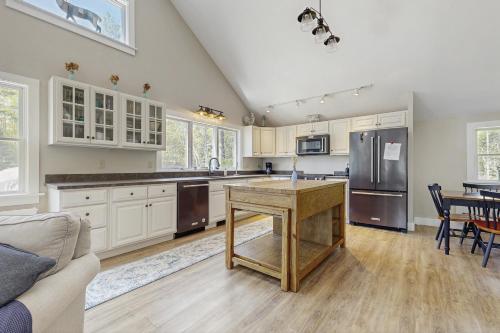 a kitchen with white cabinets and a wooden table at Hobby Hops Farmhouse in Northport