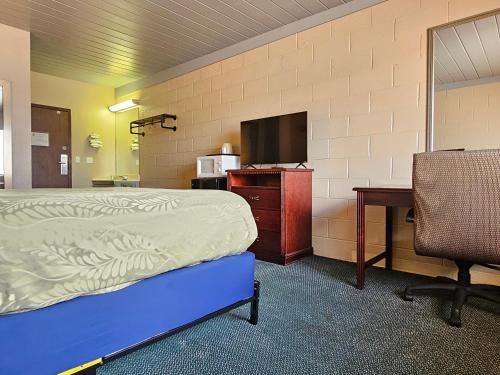 a room with a bed and a desk and a television at 1st Choice Inn of Rawlins in Rawlins