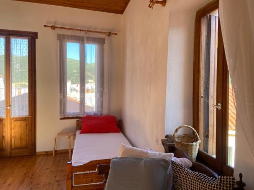 a bedroom with a bed and a couch and windows at Adele house in Skopelos Town