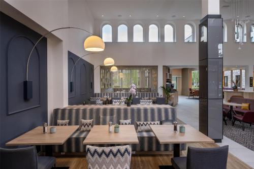 a restaurant with tables and chairs in a room at Hampton By Hilton Potsdam Babelsberg in Potsdam