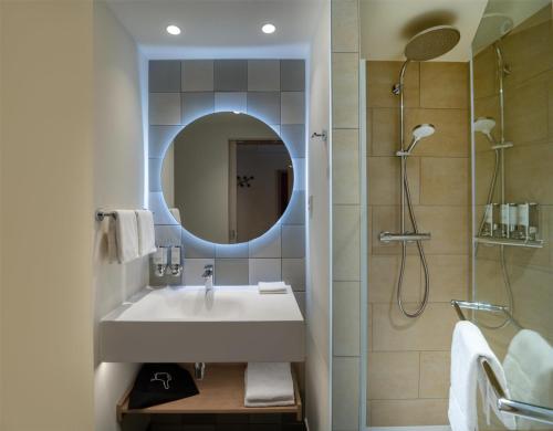 a bathroom with a sink and a shower with a mirror at Hampton By Hilton Potsdam Babelsberg in Potsdam