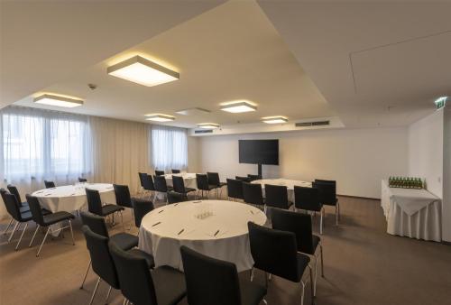 a conference room with tables and chairs and a screen at Doubletree by Hilton Vienna Schonbrunn in Vienna