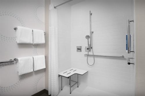 a white bathroom with a shower and a stool at Tru By Hilton Columbia Downtown in Columbia