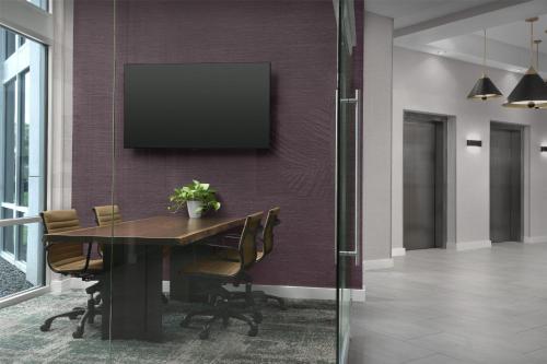 a dining room with a table and a tv on a wall at Tru By Hilton Columbia Downtown in Columbia