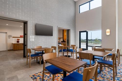 uma sala de jantar com mesas e cadeiras e uma TV em Hampton Inn By Hilton Wichita Falls North em Wichita Falls