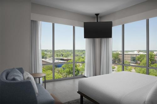 a bedroom with a bed and a chair and windows at Homewood Suites By Hilton Columbia Downtown in Columbia