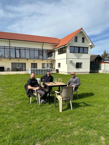 a group of people sitting at a table in the grass at Pensiunea Bibanu in Mineri