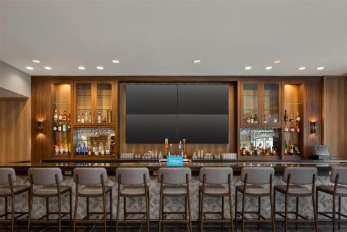 a bar with chairs in a room with a large screen at Tru By Hilton Houston Downtown Convention Center in Houston