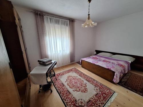 a bedroom with a bed and a table and a rug at Relax Rose Apartment in Kulen Vakuf