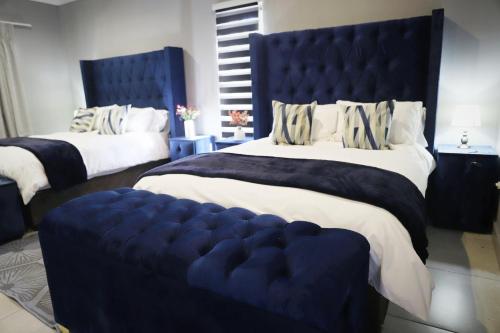 a bedroom with two beds with a large blue tufted headboard at Siyabonga Boutique Lodge in Nelspruit