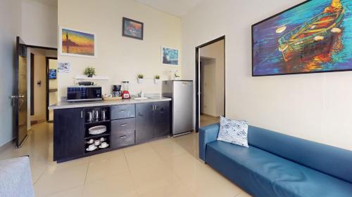 a living room with a blue couch and a kitchen at Hotel Tau Art Residence in Santo Domingo