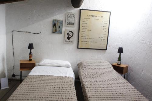 two beds in a room with two lamps and a poster on the wall at Pub house in Lucca