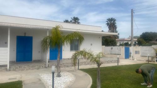a man standing in front of a house with blue doors at Casa Vacanze-Le stanze di Eolo in Marsala