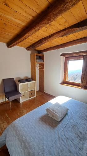 a bedroom with a bed and a chair and a window at La Casetta sotto il Monte Novegno in I Costenieri