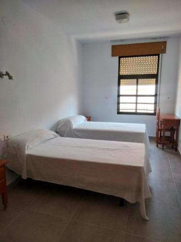 two beds in a room with a window at Hostal Extrelucía in Calzadilla