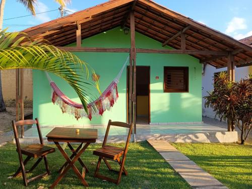 a house with two chairs and a table in front of it at Chalés do Otto e Karine in Canoa Quebrada