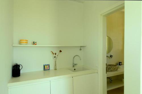 a white bathroom with a sink and a mirror at Island residence in Logothetiánika
