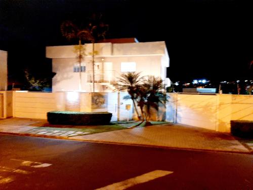 a white building with a palm tree in front of it at Apto Inteiro em Atibaia do lado da Av Lucas Bairro Nobre in Atibaia