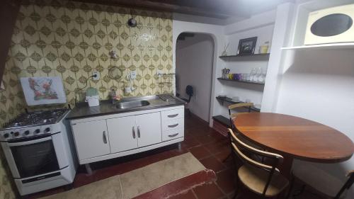 a small kitchen with a table and a stove at CASA DO BRAZ aptos e casa de temporada in Monte Verde