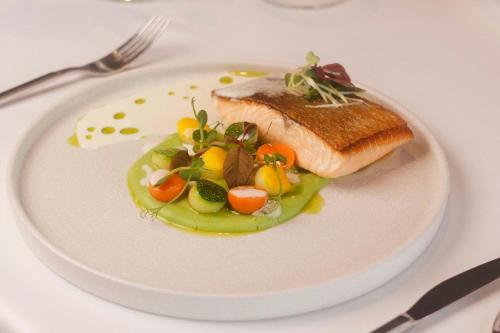 a white plate with a piece of fish and vegetables at Fairfield by Marriott South Binh Duong in Thuan An