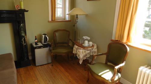 ein Wohnzimmer mit 2 Stühlen, einem Tisch und einer Lampe in der Unterkunft B&B Dreamcottage in Knokke-Heist