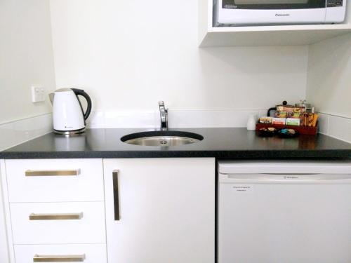 a kitchen counter with a sink and a microwave at Airport Palms Motel in Christchurch