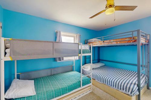 two bunk beds in a blue room with a ceiling fan at Seashore Cove in North Topsail Beach