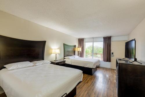 a hotel room with two beds and a flat screen tv at Executive Inn in Beeville