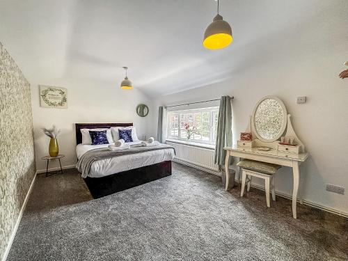 a bedroom with a bed and a mirror and a table at Yellow House Cottage in Southport